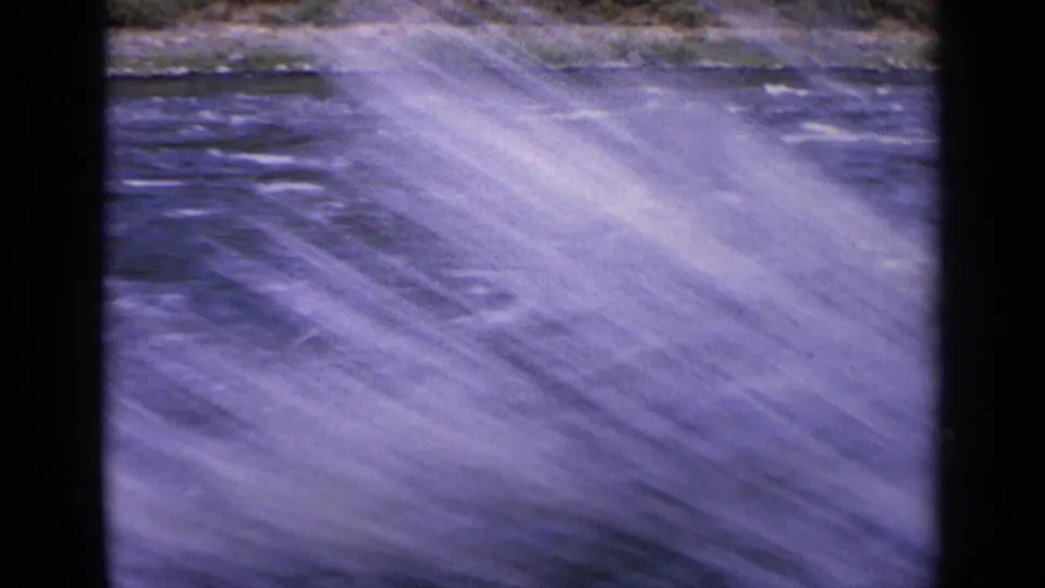 1963 Idaho 8mm frame showing white spray over fast blue water, softened by motion blur from the passing viewpoint.
