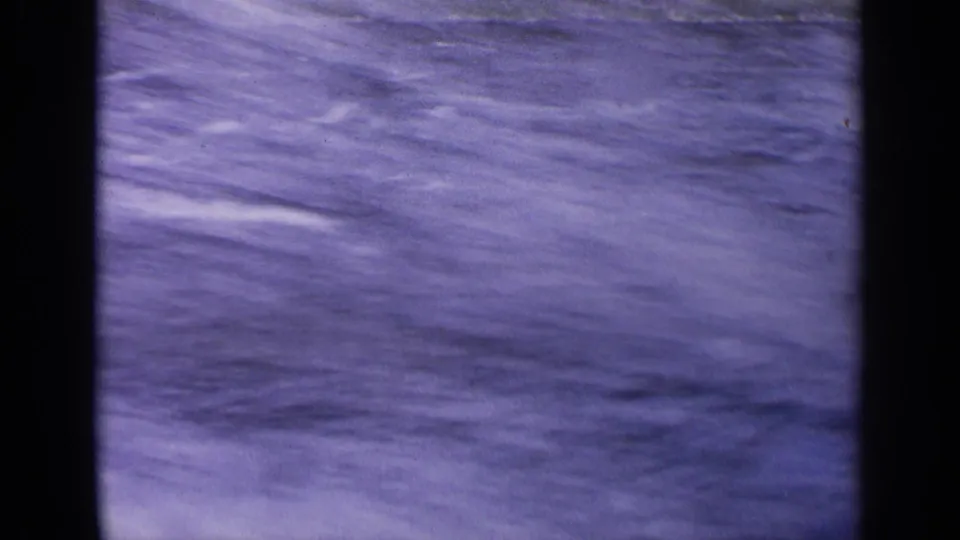 1963 Idaho home-movie frame with blurred blue water and pale ripples filling most of the view.