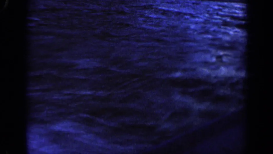 1963 Idaho 8mm frame of dark blue rippled water, with a shadowed foreground edge and visible film-frame borders.