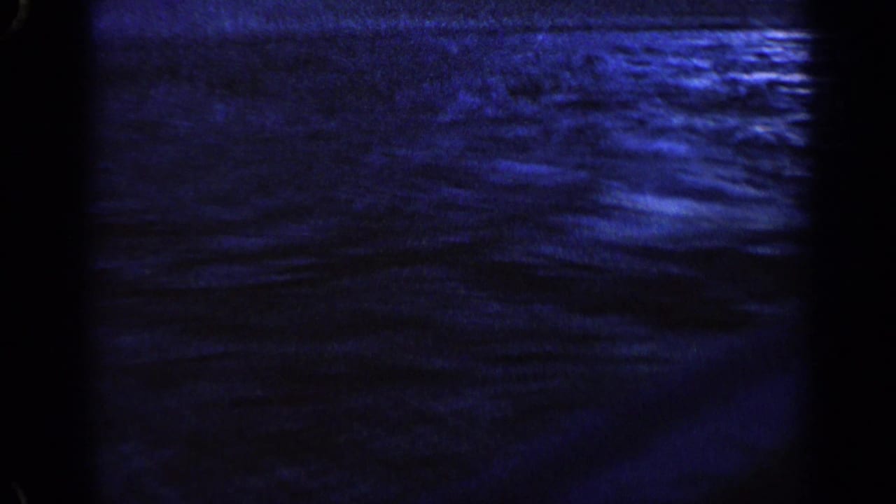 Dark blue rippling water seen from a fast-moving boat with frame borders visible.