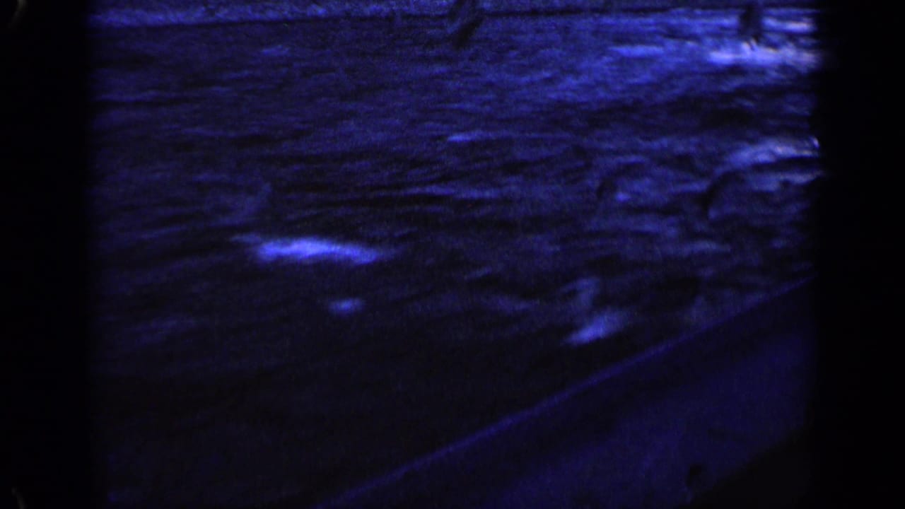 A side view from a moving boat shows blue wake, splashes, and a dark boat edge in 1963 home-movie footage.