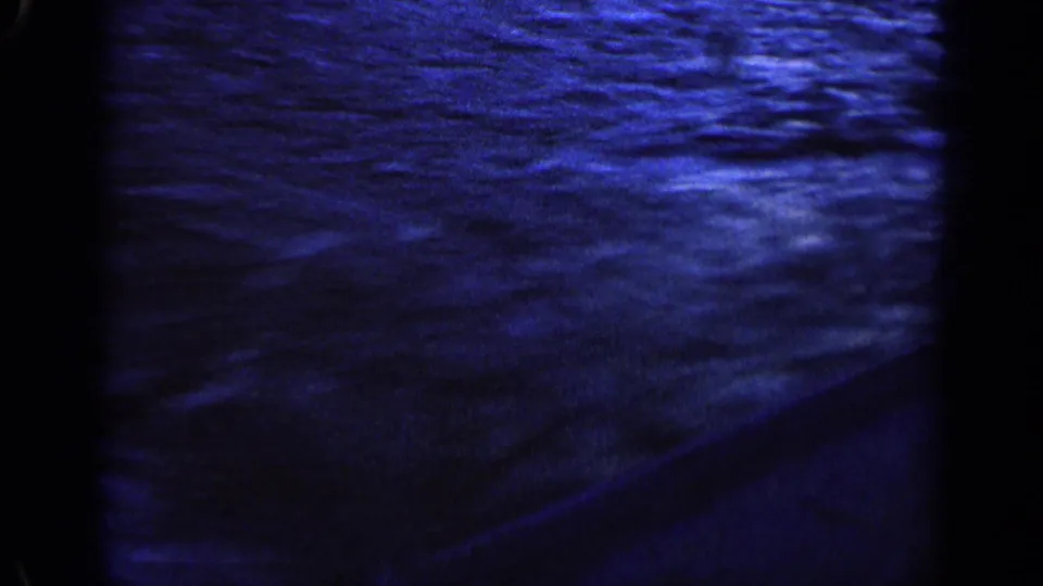The camera looks down at fast blue water and a dark boat edge during likely Idaho boating footage from 1963.