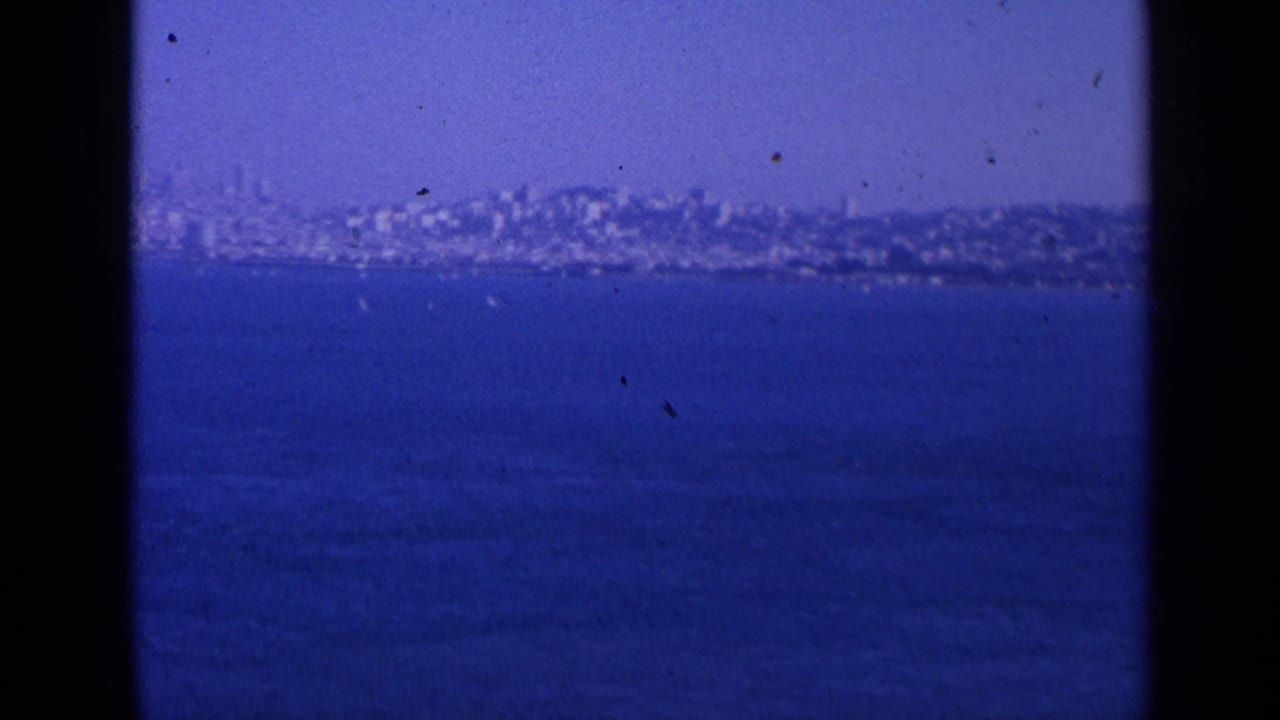 San Francisco appears in the distance across the bay, with hillside buildings, blue water, open sky, and 8mm scan borders.