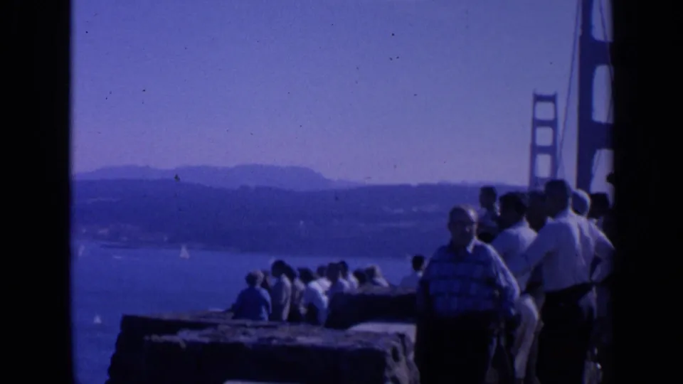 1963 San Francisco view of tourists in period clothing watching the bay near the Golden Gate Bridge.