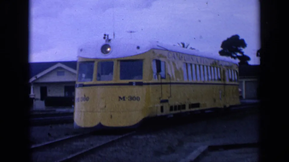 1963 San Francisco frame with the yellow M-300 railcar near the foreground, houses and trees behind it.