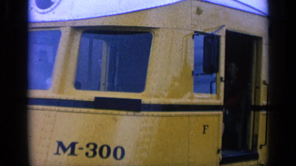 Yellow M-300 railcar fills the frame as a passenger stands partly visible in the open doorway in 1963 San Francisco footage.