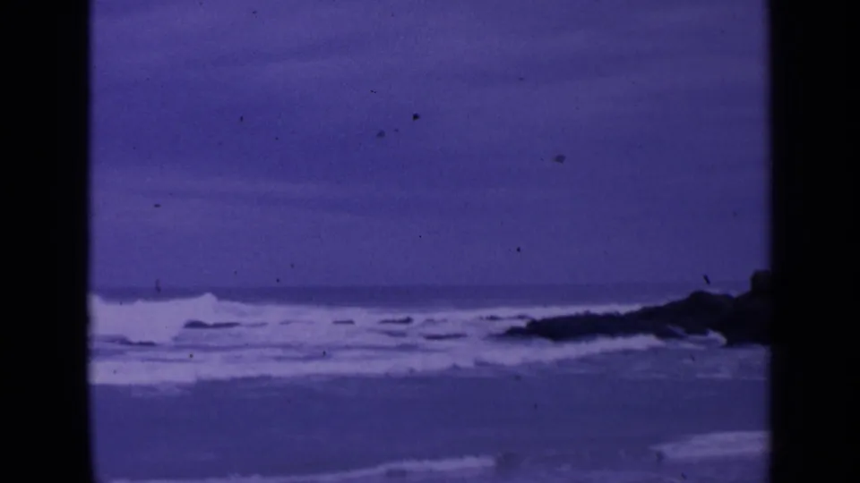 Rough coastal water and dark rocks appear in a 1963 San Francisco 8mm frame with visible grain and dust.