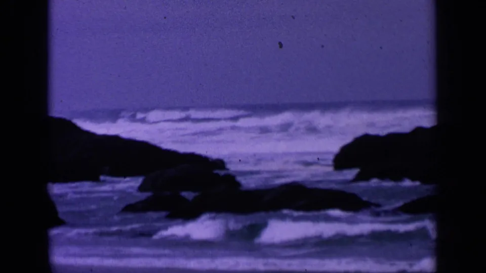 1963 8mm coastal view near San Francisco showing white surf moving between dark offshore rocks.