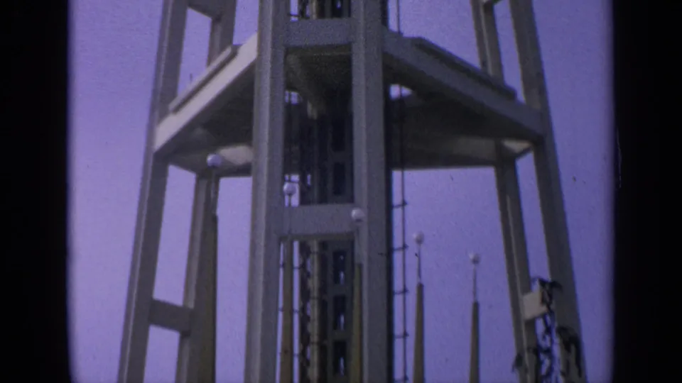 1963 8mm view of the lower Space Needle structure in Washington, framed from below against a clear sky.