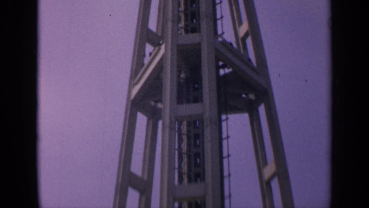 Low-angle view of the upper section of a steel tower against a purple sky.