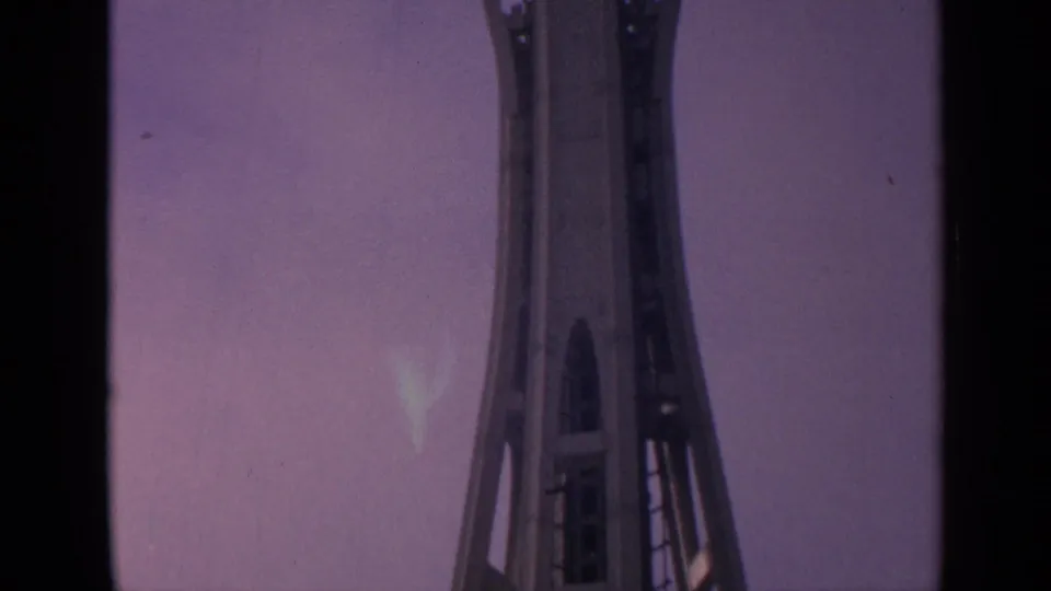 1963 8mm frame showing the lower portion of a Washington steel tower with angled legs and soft sky color.
