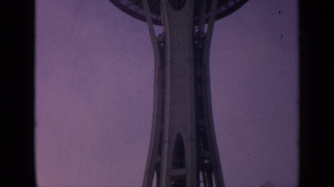Low-angle view of the Space Needle shaft against a purple sky.