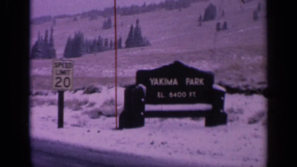 1963 Washington 8mm frame showing a snowy Yakima Park roadside sign with a speed limit sign nearby.