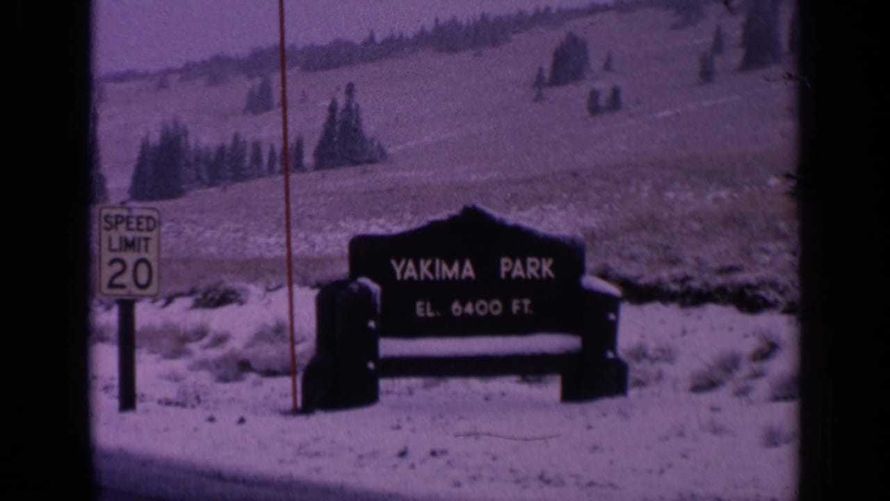 1963 Washington frame of the Yakima Park sign and elevation text, filmed from a roadside with snow, evergreens, and visible 8mm frame edges.
