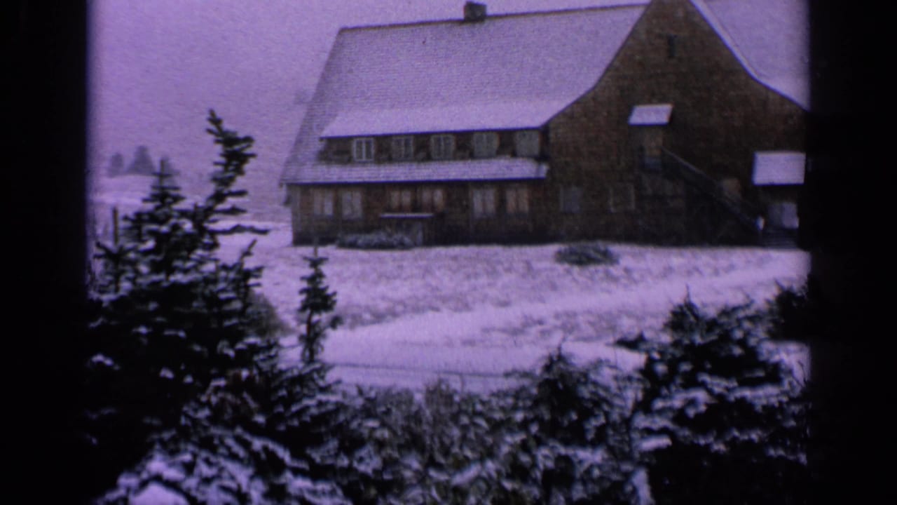 1963 Washington 8mm frame of a snow-dusted lodge exterior with evergreen trees and a pale winter sky.