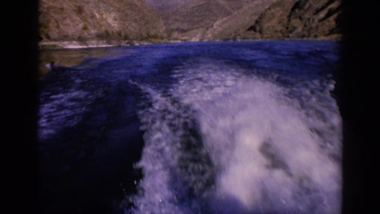 1963 Washington home-movie frame with turbulent white water in the foreground and arid rocky hills beyond the river.