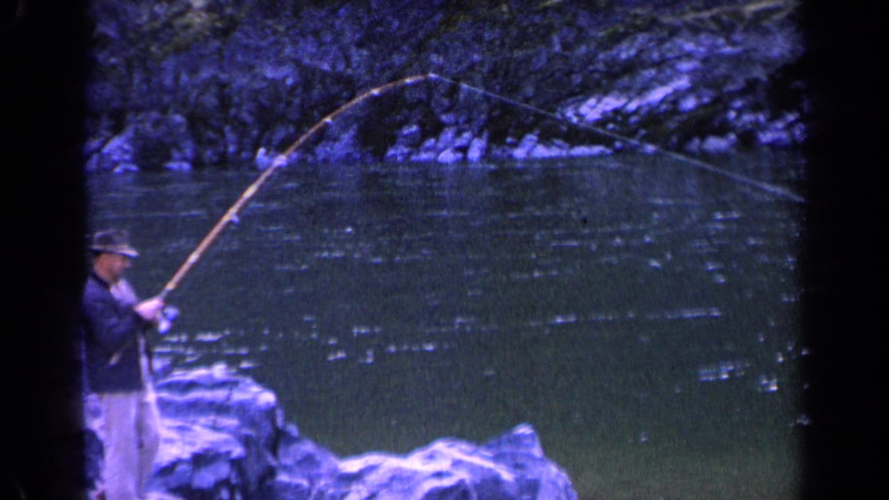The fisherman remains partly framed at the lower left as his long pole arcs across the river in blue-purple 8mm footage.