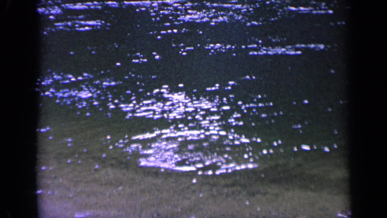 Sunlit shallow water with scattered highlights and a small disturbance near the center.