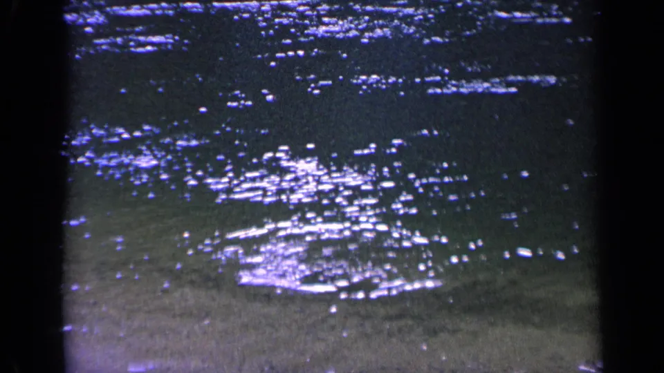 1963 Washington 8mm frame with shimmering highlights across shallow water and a faint splash pattern near shore.