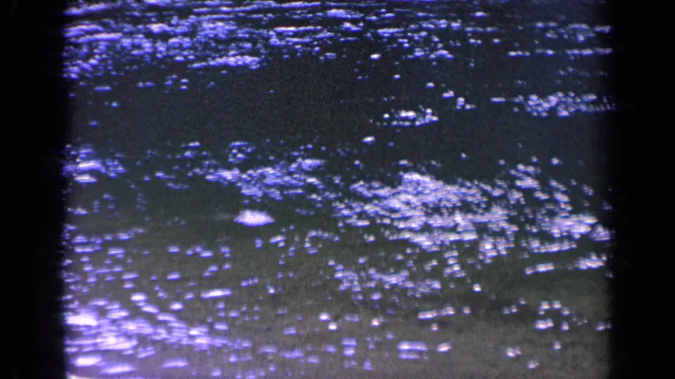 1963 Washington 8mm frame showing purple-blue water ripples with bright reflected highlights and soft film grain.