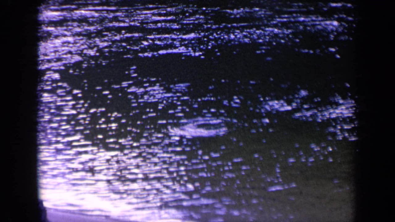 1963 Washington 8mm frame of dense purple-blue water ripples with shimmering reflected light and visible film grain.