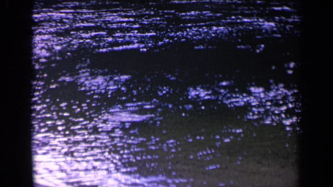 1963 8mm home-movie frame from Washington showing rippling green-blue water with shimmering reflected light and dark film edges.