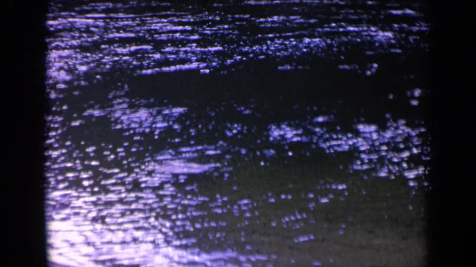 1963 8mm home-movie frame from Washington showing rippling green-blue water with shimmering reflected light and dark film edges.