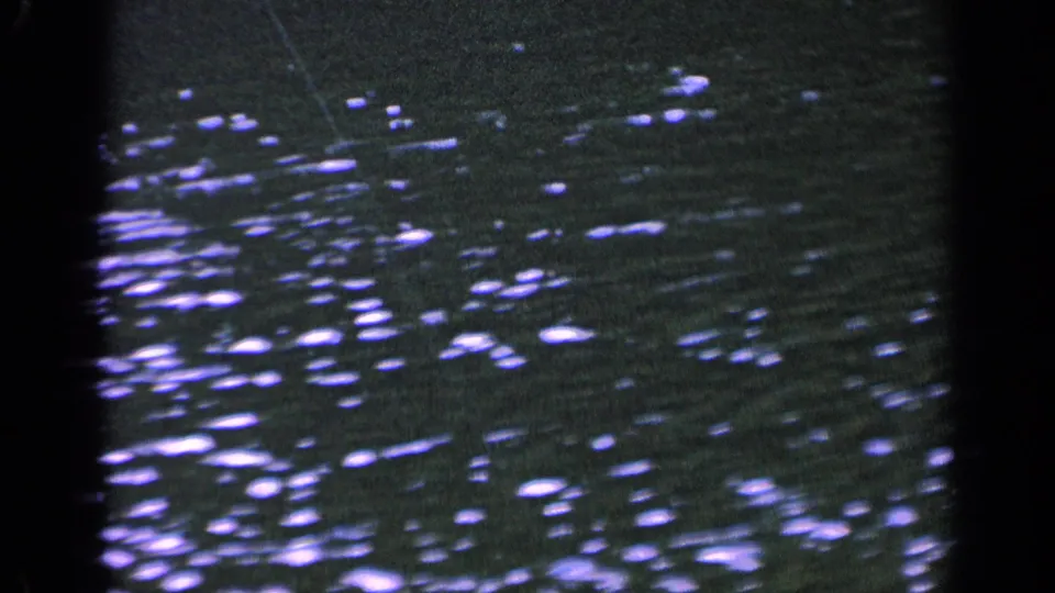1963 Washington 8mm frame showing rippled lake water with scattered bright reflections and dark frame edges from the film scan.