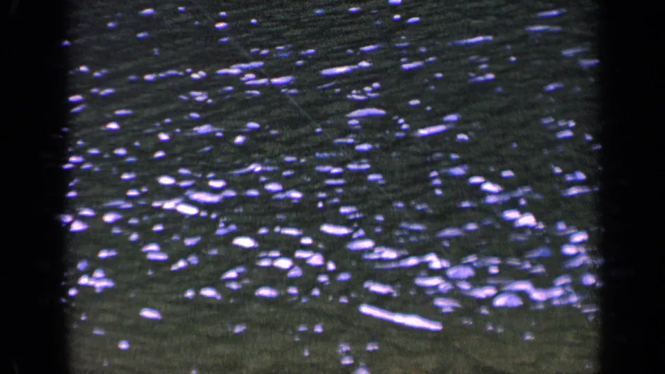1963 Washington 8mm frame showing a close, abstract view of rippling lake water with bright highlights and visible film grain.