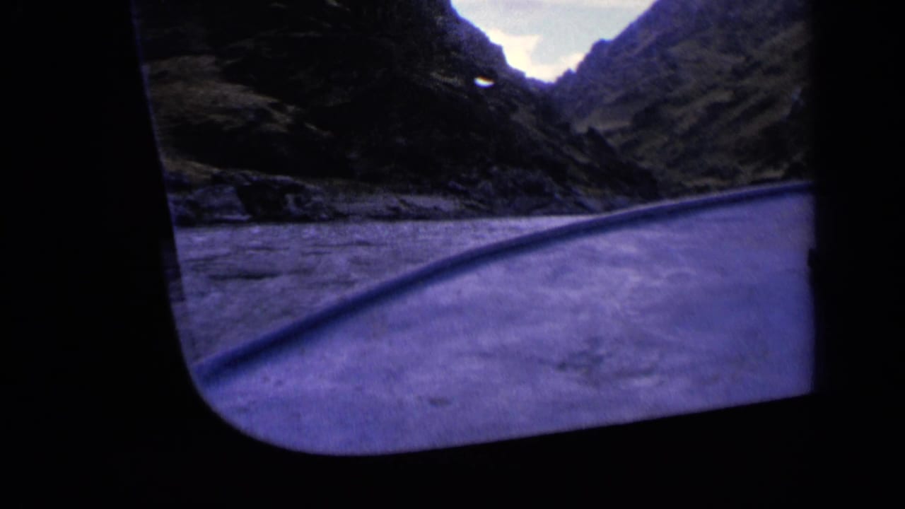 Boat deck edge crossing rippled canyon water beneath steep dark slopes.
