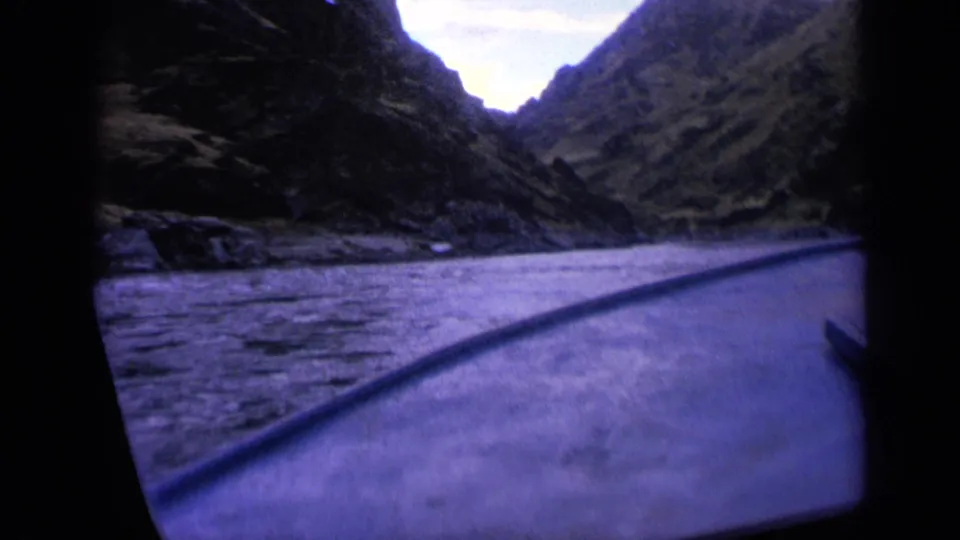 1963 Washington home-movie view from a boat, showing the deck edge, lake surface, and canyon walls under a pale sky.