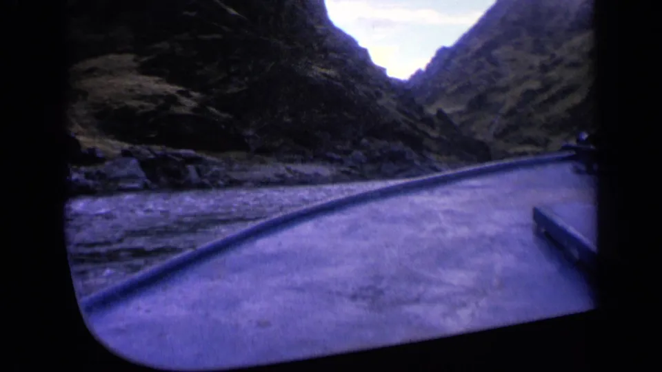 Washington 1963 8mm frame with a passenger view over a boat deck toward rippled canyon water and dark rocky hillsides.