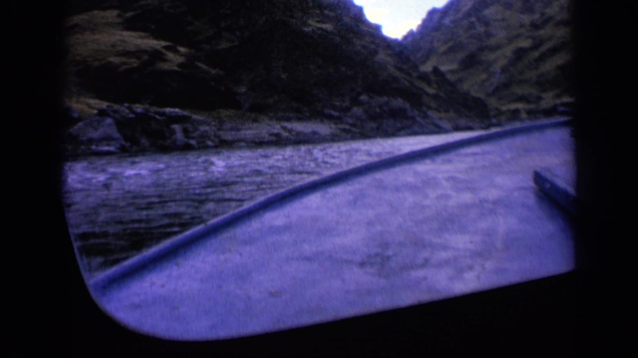 1963 Washington 8mm frame showing a boat bow entering a narrow, shadowed river gorge with steep rocky slopes on both sides.