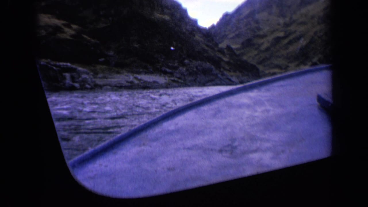 1963 Washington home-movie frame from a moving boat, with the bow pointed toward a narrow mountain gorge and turbulent water alongside.