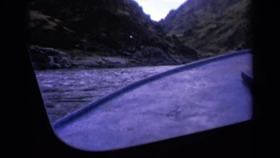 1963 Washington home-movie frame from a moving boat, with the bow pointed toward a narrow mountain gorge and turbulent water alongside.