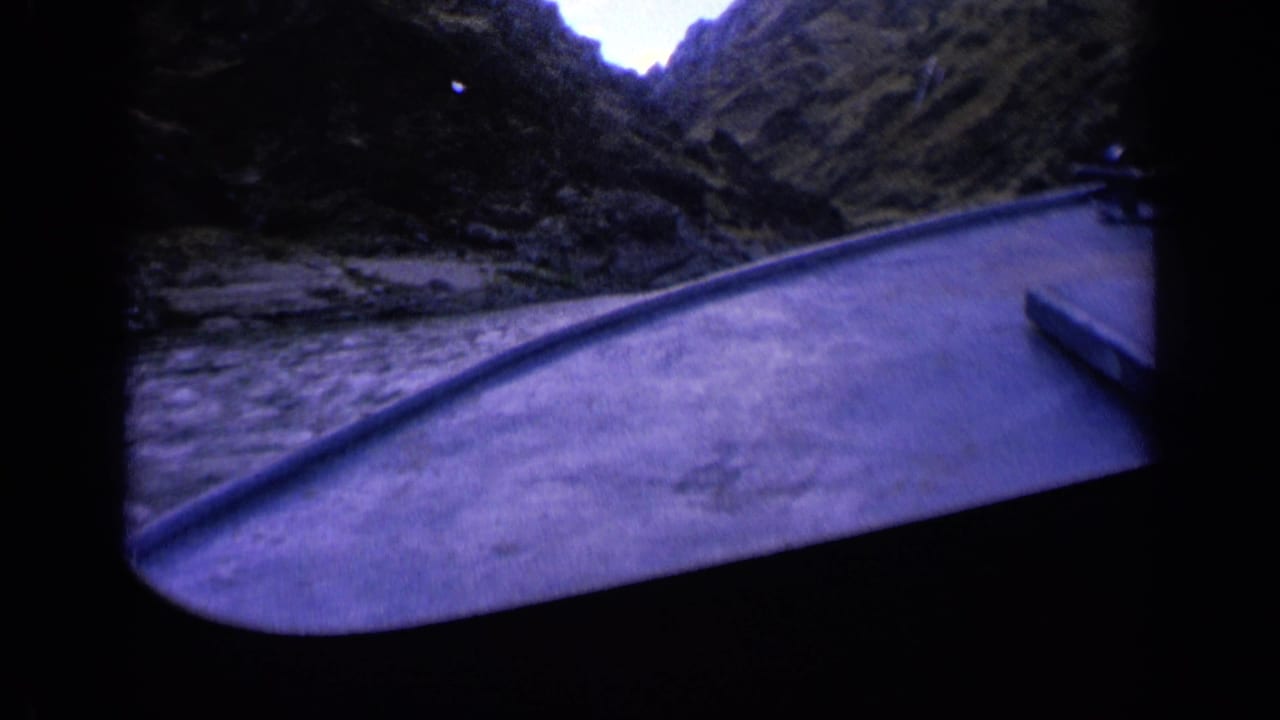1963 Washington frame showing the boat bow and churning river water under steep, dark mountain walls with a cool blue film cast.