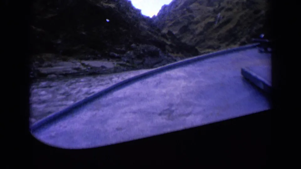 1963 Washington frame showing the boat bow and churning river water under steep, dark mountain walls with a cool blue film cast.