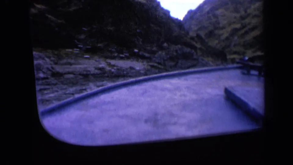 Home-movie frame from Washington showing a boat perspective along a river bordered by steep rocky hillsides.