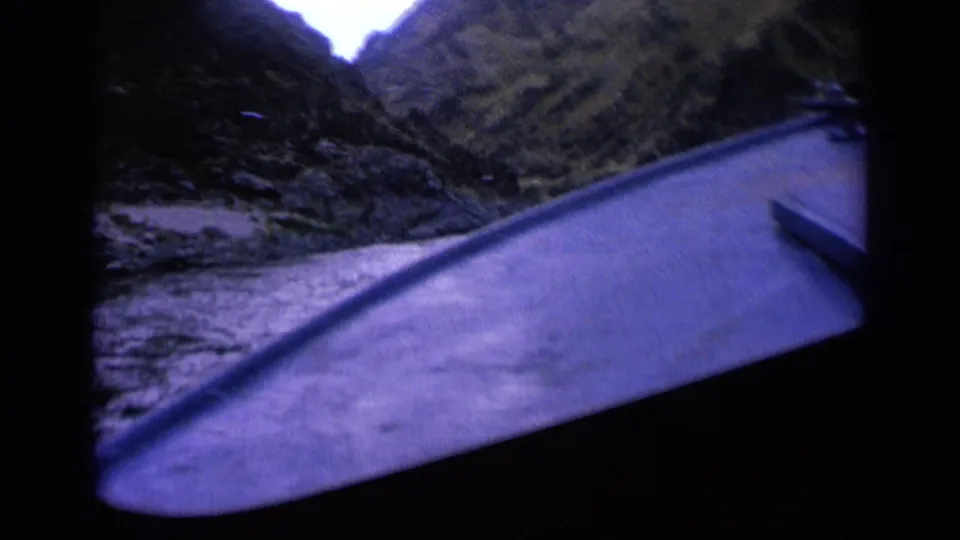 Vintage 8mm boat POV in Washington, with the bow entering a river bend beneath steep canyon hills.