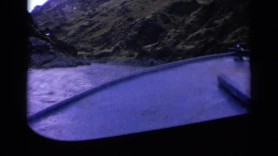 1963 Washington home-movie frame looking over a boat bow at a river running through steep rocky canyon terrain.