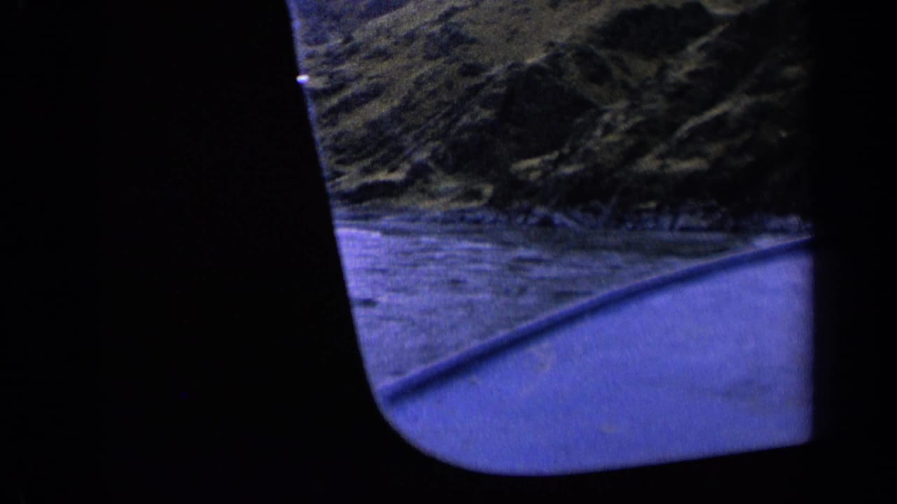Boat-level 8mm view in Washington, 1963, with a curved blue edge, water, and dark hillside scenery.