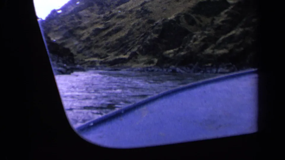 Washington 1963 home-movie frame with boat trim, rippled water, and a steep natural shoreline.