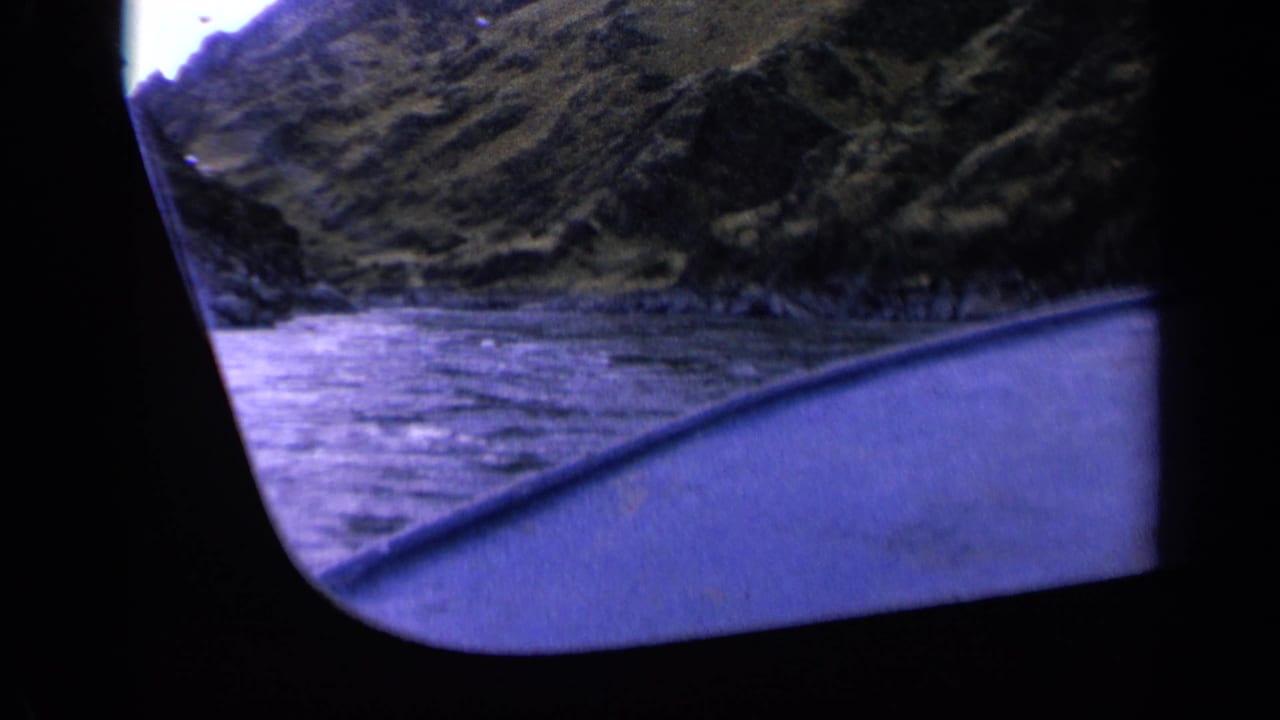 River valley seen from a vessel with a dark window edge and blue-toned water.