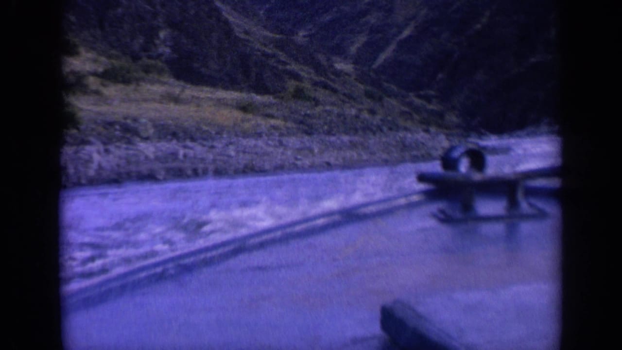 1963 Washington 8mm frame showing a boat fixture near the right edge as the vessel passes a rocky bank and steep hillside.