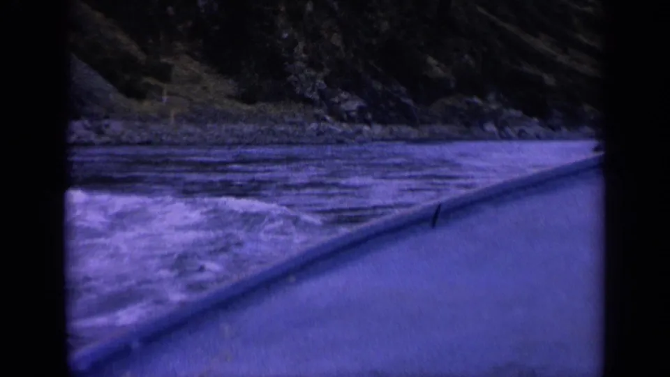 1963 Washington 8mm frame showing churning blue water, rocky shore, and a sloped foreground vessel edge with strong color shift.