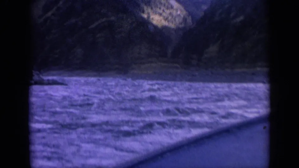 The boat continues through fast-moving river water, with blurred canyon slopes and window borders visible in the 1963 footage.