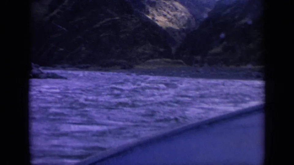 A passenger-facing view shows churning river water, a boat edge, and dark canyon slopes in 1963 Washington home-movie footage.