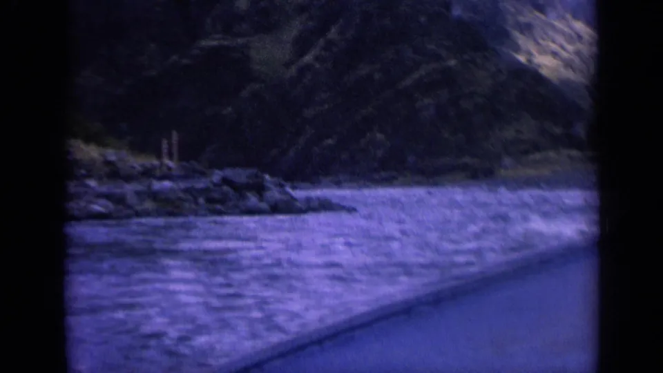 Moving 8mm view of a Washington river corridor with rocky shoreline, wooded slopes, and window framing.
