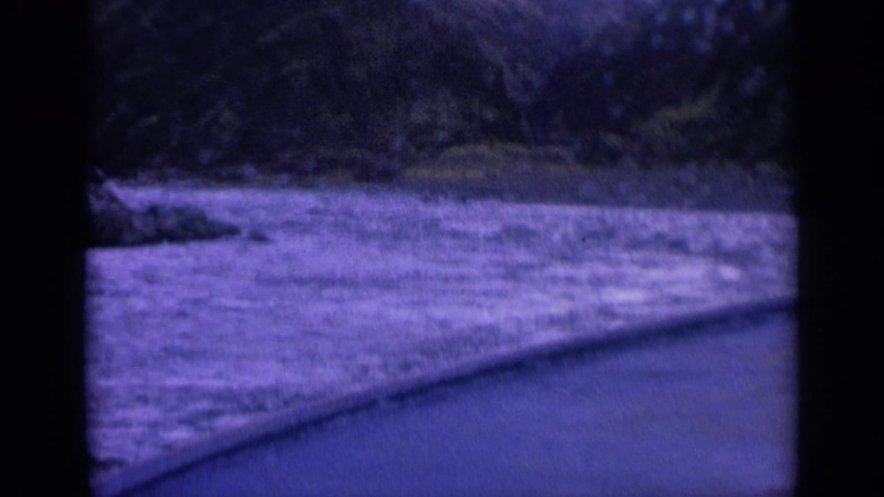 1963 Washington 8mm frame showing turbulent river water from a boat, with shoreline beyond and dark film borders visible.