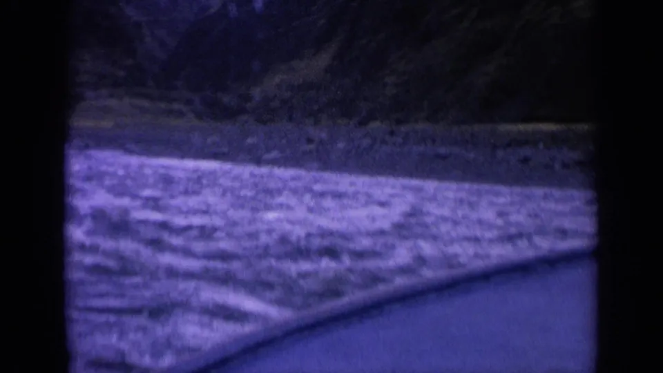 1963 Washington home-movie frame showing rough river surface near the boat, with a dark wooded bank beyond.